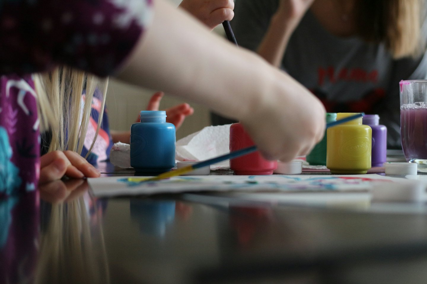 Kinder malen mit bunten Flaschen und Pinseln.